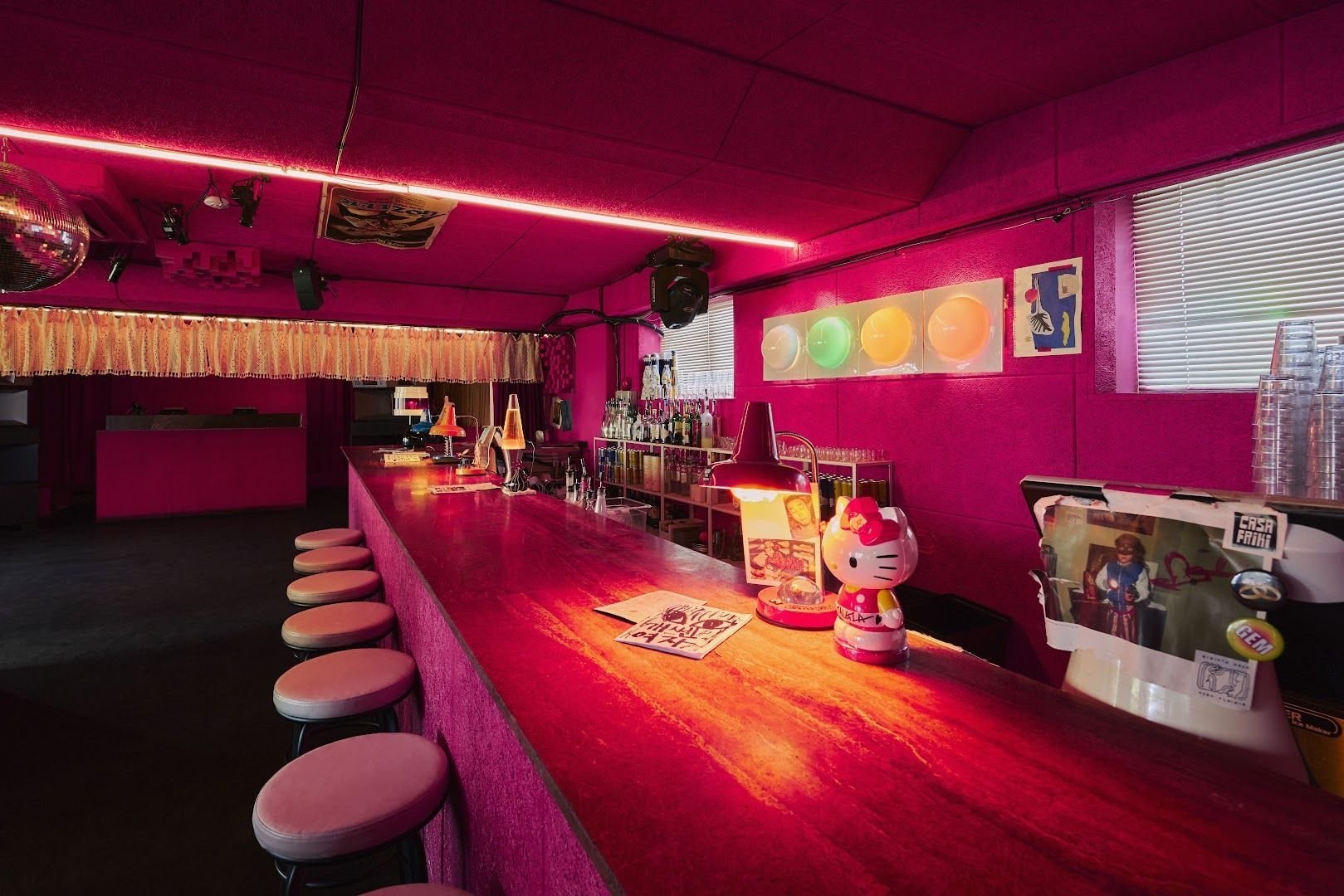 NYAPI’s long pink bar counter, stools and illuminated wall art.